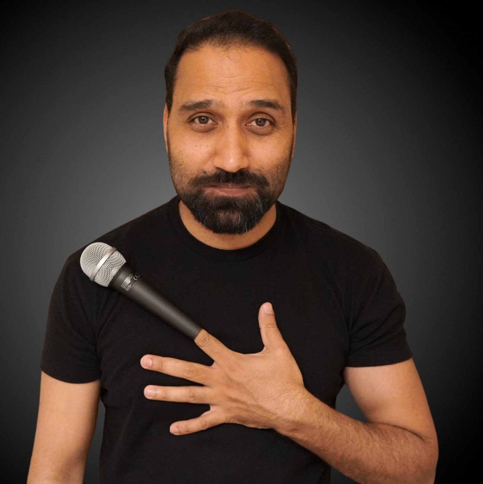 Ish (Ishtiaq Qureshi) performing stand-up with a microphone